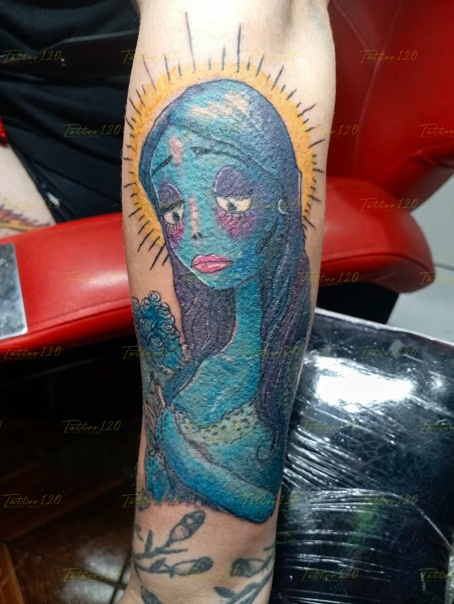 Tatuaje a color en el brazo del personaje Emily de El cadáver de la novia de Tim Burton, detallado en tonos azules con un resplandor amarillo alrededor de su cabeza. estilo anime, manga e ilustraciones, realizado en el estudio Tattoo120 en Colina, Región Metropolitana.