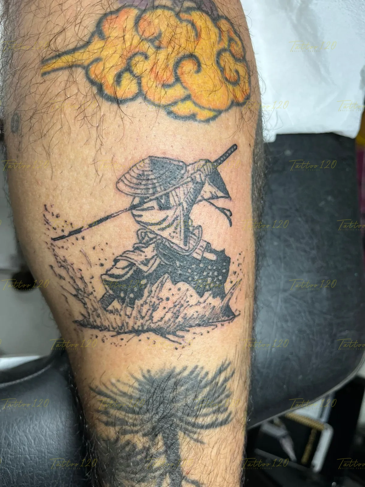 Tatuaje de estilo anime en la pierna que representa a un pequeño guerrero samurái con sombrero cónico rompiendo una ola, realizado en tinta negra con sombreados. estilo anime, manga e ilustraciones, realizado en el estudio Tattoo120 en Colina, Región Metropolitana.