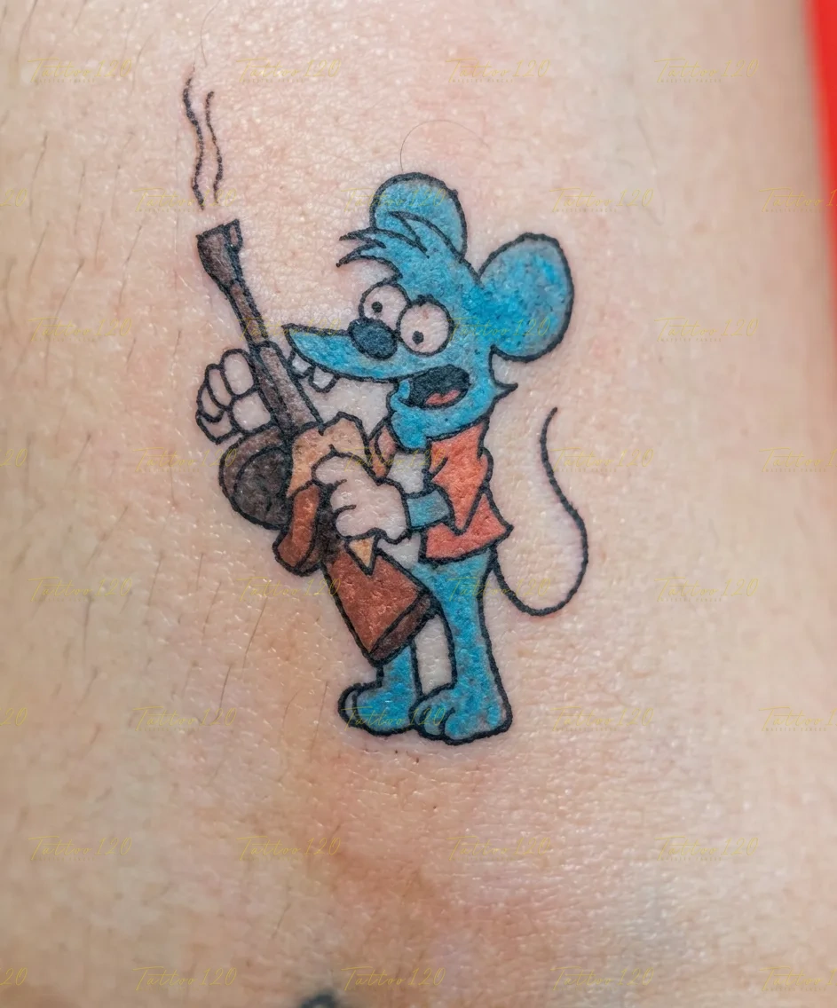 Tatuaje pequeño a color del ratón Pica (Itchy) de Los Simpson sosteniendo un fusil humeante, delineado en negro y relleno con tonos azul y naranja. estilo anime, manga e ilustraciones, realizado en el estudio Tattoo120 en Colina, Región Metropolitana.