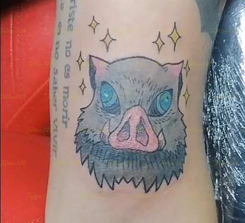 Tatuaje a color de la máscara de jabalí de Inosuke Hashibira de Demon Slayer, con ojos azules brillantes y destellos amarillos alrededor. estilo anime, manga e ilustraciones, realizado en el estudio Tattoo120 en Colina, Región Metropolitana.