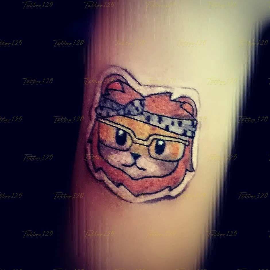 Tatuaje pequeño de estilo tierno o kawaii que muestra la cabeza de un león con lentes y un pañuelo estampado en la frente, con un delineado estilo pegatina. estilo anime, manga e ilustraciones, realizado en el estudio Tattoo120 en Colina, Región Metropolitana.
