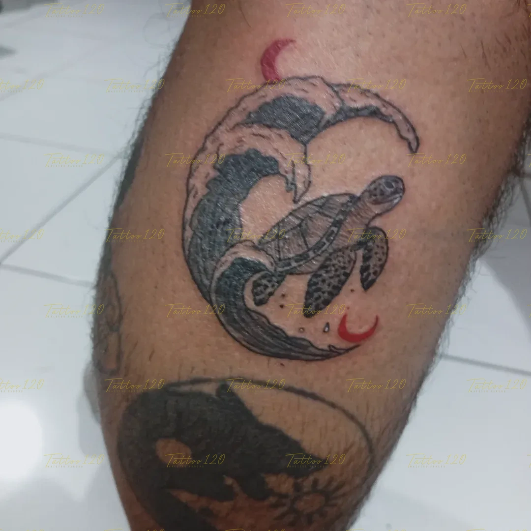 Tatuaje circular que representa a una tortuga marina nadando junto a una ola detallada en tinta negra y pequeñas lunas rojas, en estilo de línea fina y minimalistas, realizado en el estudio Tattoo120 en Colina, Región Metropolitana.
