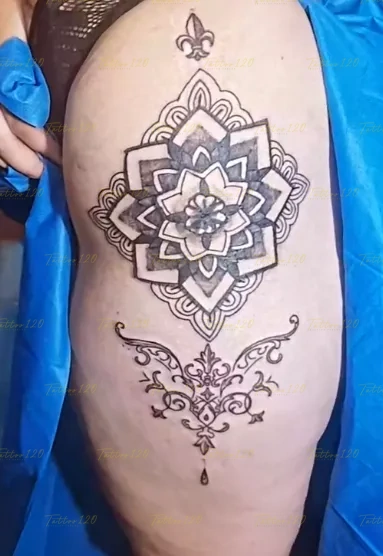 Tatuaje grande en la cadera o muslo con un diseño de mandala geométrico simétrico acompañado de ornamentos inferiores, en estilo de línea fina y minimalistas, realizado en el estudio Tattoo120 en Colina, Región Metropolitana.