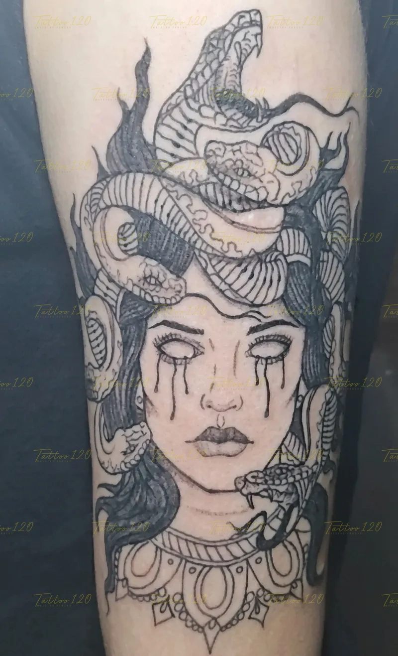 Tatuaje detallado del rostro de Medusa con serpientes en la cabeza y lágrimas negras cayendo de sus ojos, delineado en tinta negra, en estilo de línea fina y minimalistas, realizado en el estudio Tattoo120 en Colina, Región Metropolitana.