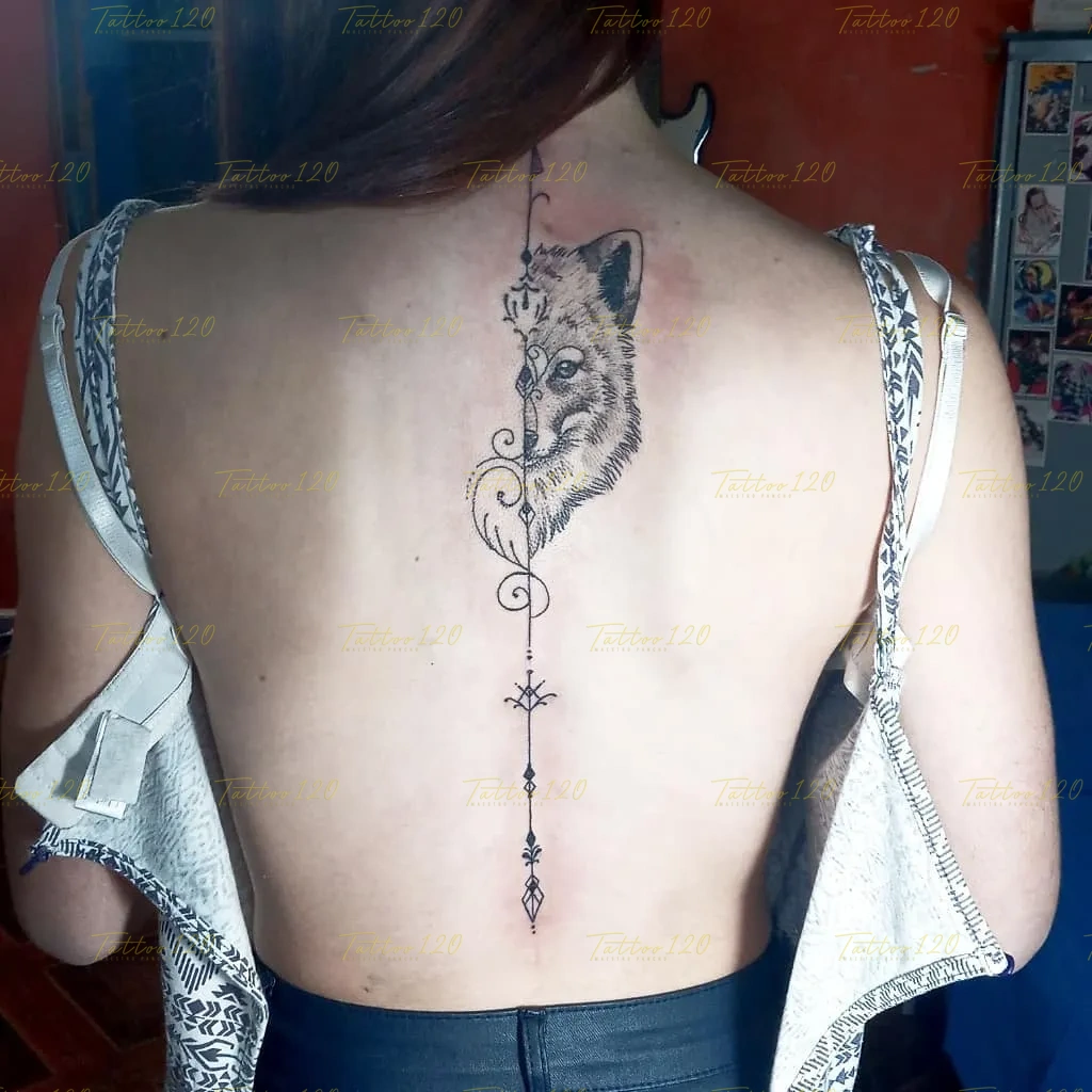 Tatuaje vertical en la espalda que muestra la mitad del rostro de un lobo decorado con ornamentos y extendido con un diseño ornamental unalome, en estilo de línea fina y minimalistas, realizado en el estudio Tattoo120 en Colina, Región Metropolitana.