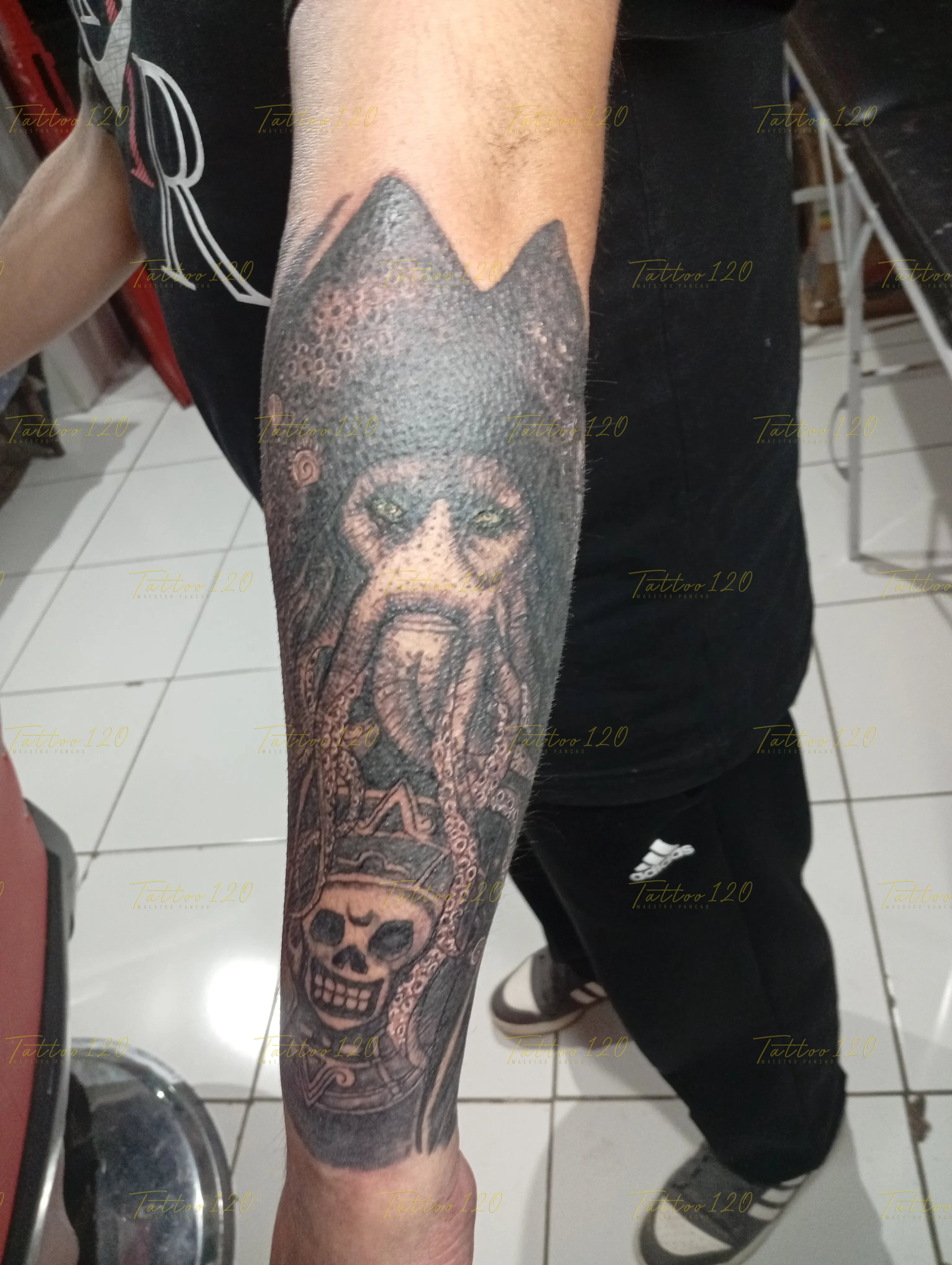 Tatuaje realista en el antebrazo del personaje Davy Jones con sus tentáculos característicos sobre un cofre con un cráneo pirata, en estilo de realistas, retratos y sombras, realizado en el estudio Tattoo120 en Colina, Región Metropolitana.