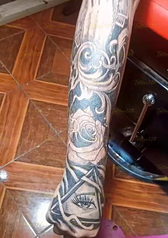 Tatuaje que se extiende por el antebrazo con una rosa difuminada y termina en el dorso de la mano con un ojo realista, en estilo de realistas, retratos y sombras, realizado en el estudio Tattoo120 en Colina, Región Metropolitana.