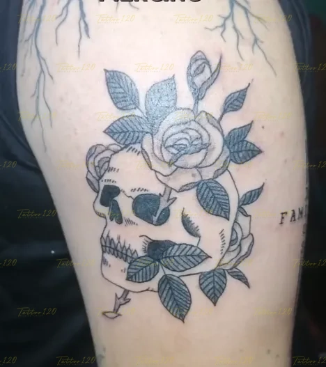 Tatuaje lineal con sombras sutiles que representa un cráneo humano rodeado por ramas y flores de rosas en el brazo, en estilo de realistas, retratos y sombras, realizado en el estudio Tattoo120 en Colina, Región Metropolitana.