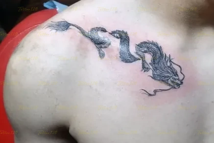 Tatuaje detallado en la zona de la clavícula y hombro que muestra un dragón oriental alargado con escamas y bigotes definidos, en estilo de realistas, retratos y sombras, realizado en el estudio Tattoo120 en Colina, Región Metropolitana.