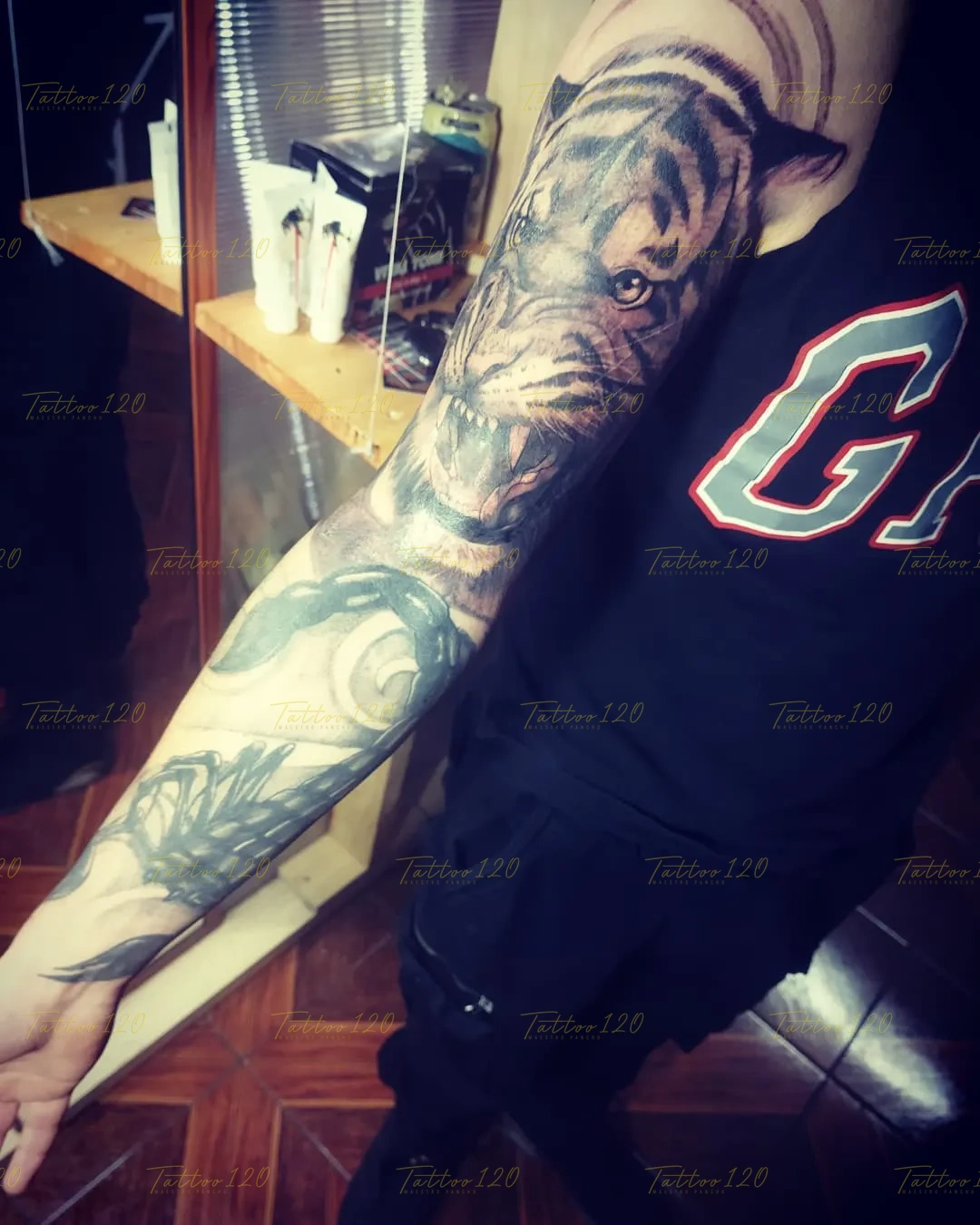 Tatuaje de manga completa en el brazo que destaca la cabeza de un tigre rugiendo con texturas de pelaje detalladas y sombras densas, en estilo de realistas, retratos y sombras, realizado en el estudio Tattoo120 en Colina, Región Metropolitana.