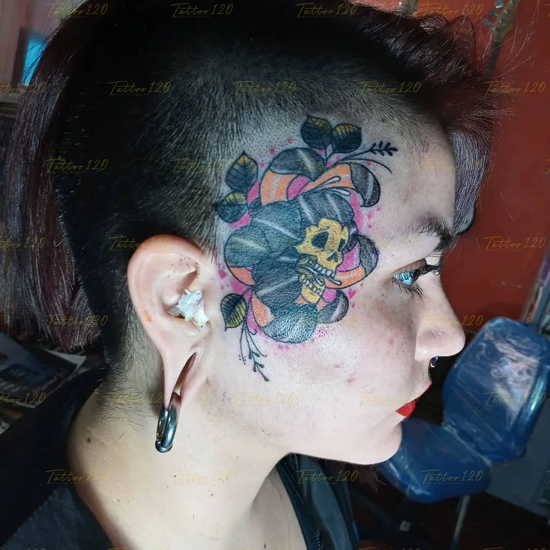 Tatuaje en la sien y cabeza de una calavera amarilla integrada dentro de una gran flor negra con hojas y fondo rosa, en estilo de tradicional y neo tradicional, realizado en el estudio Tattoo120 en Colina, Región Metropolitana.